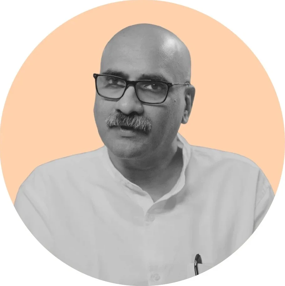 A black-and-white cut-out on a circular ground: bald, with a moustache and rectangular glasses, in a white collarless shirt.